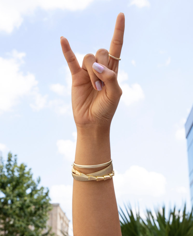 A woman's hand giving the Hook 'em Horns sign
