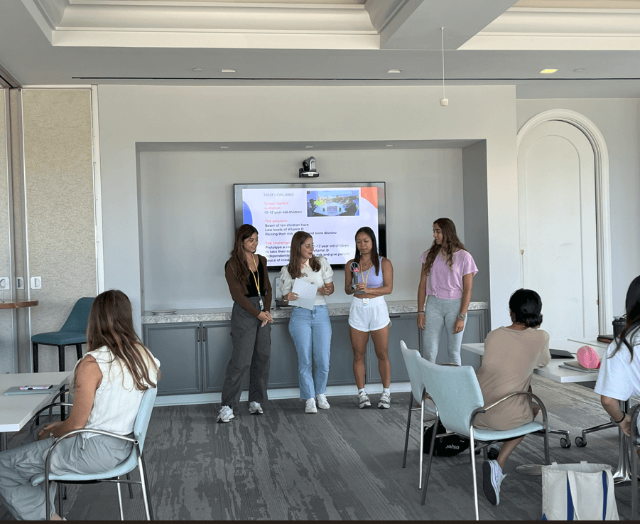 Group of people presenting to a group standing in front of a TV.
